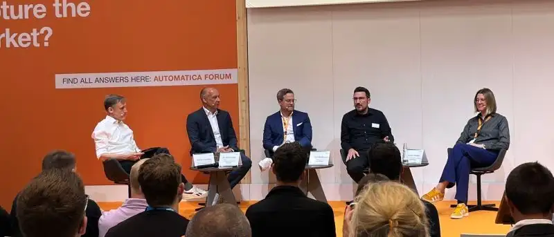 Podiumsdiskussion auf einer Messebühne vor Publikum.