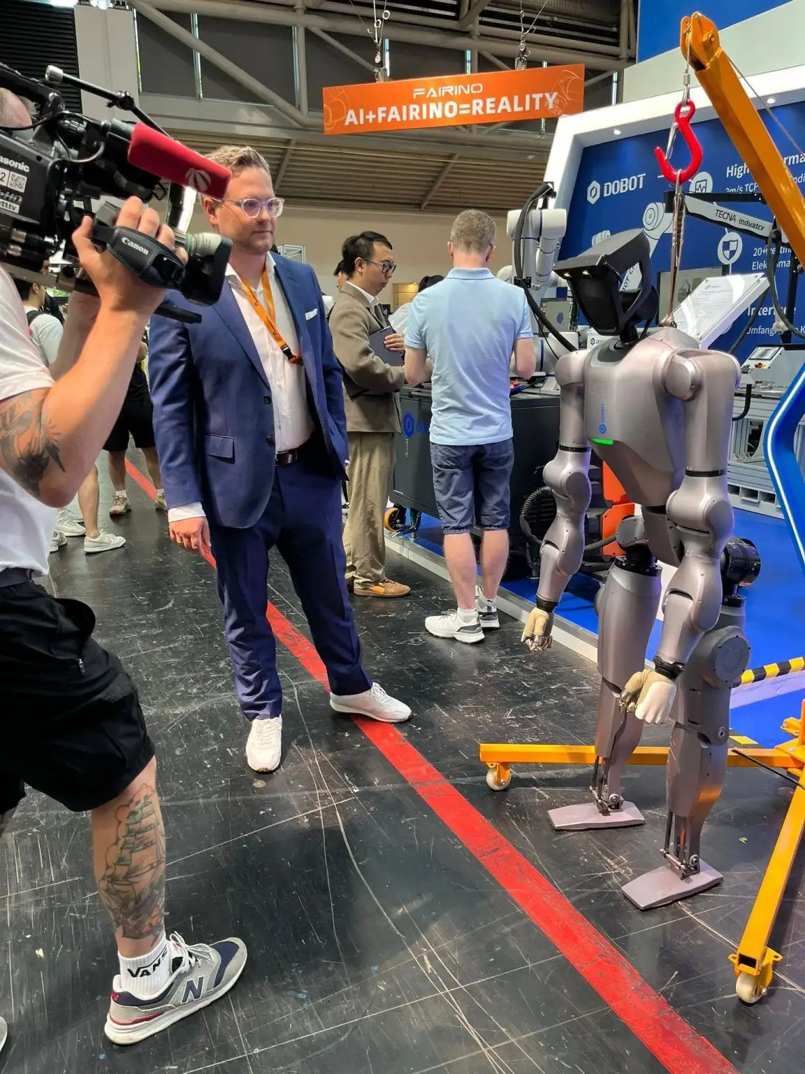 Interview- und Filmsituation an einem Messestand mit mehreren Beteiligten.