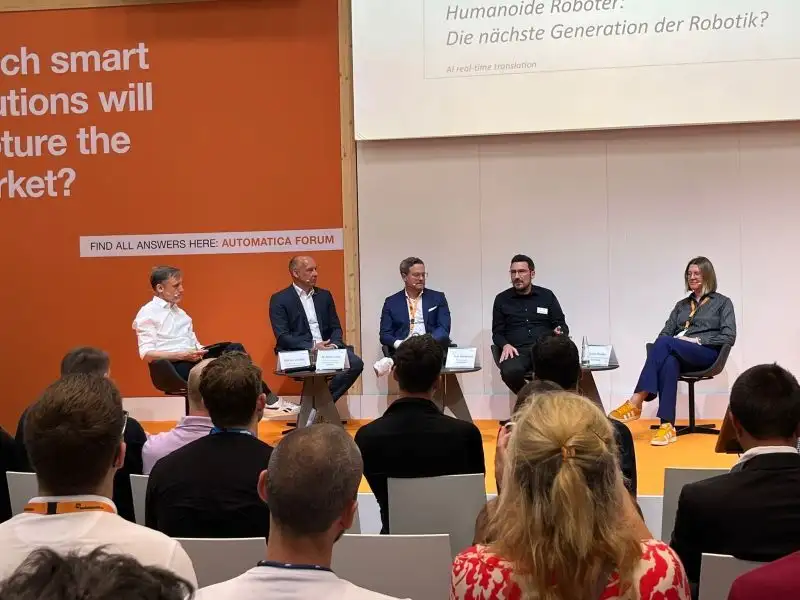 Podiumsdiskussion auf einer Messebühne vor Publikum.