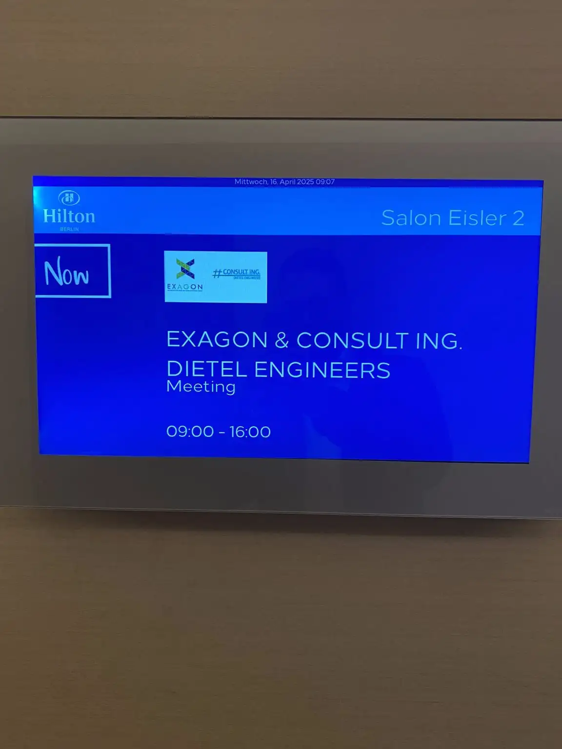 Bildschirm im Hotel mit Meeting-Informationen und Zeitplan.