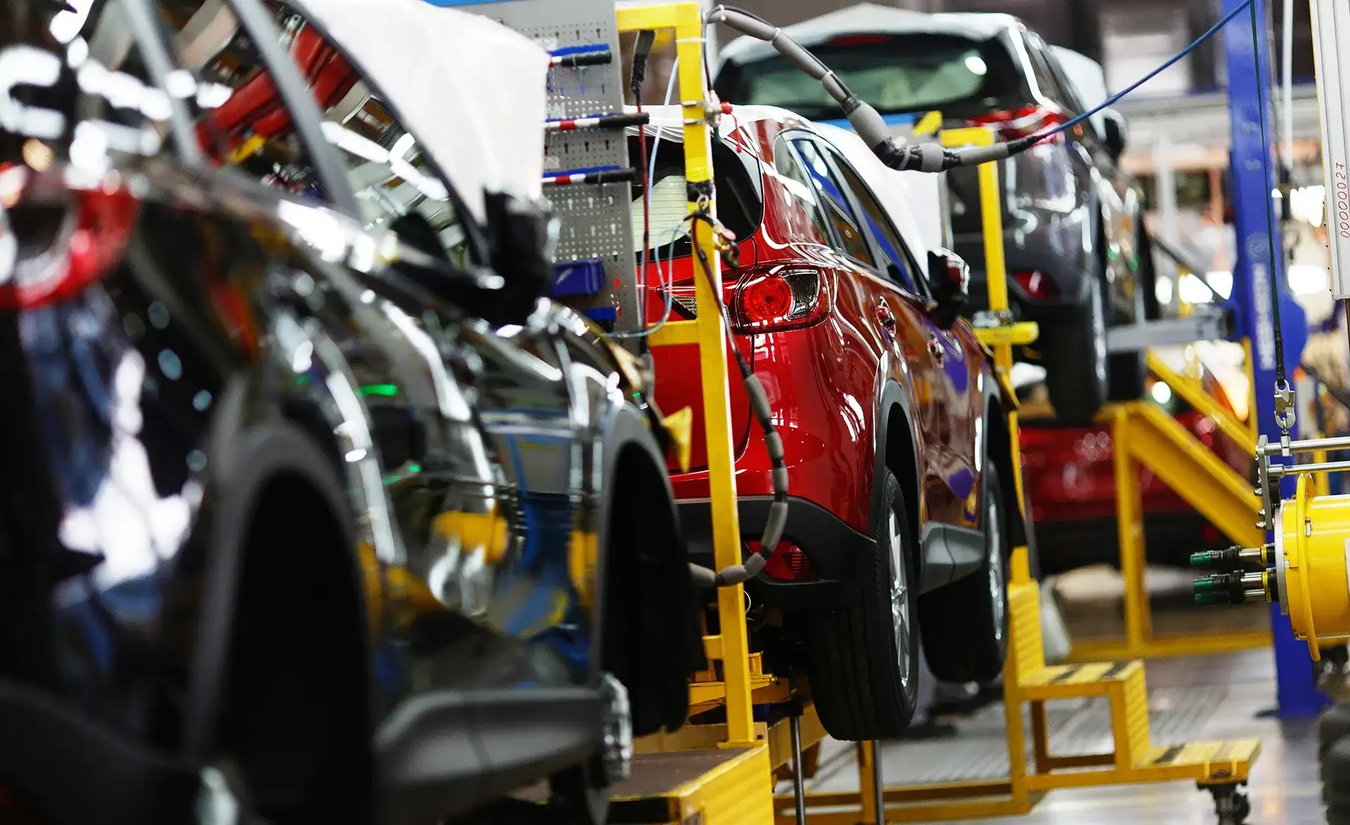 Mehrere Fahrzeuge stehen in einer Automobilfertigungslinie, während Montagearbeiten durchgeführt werden.