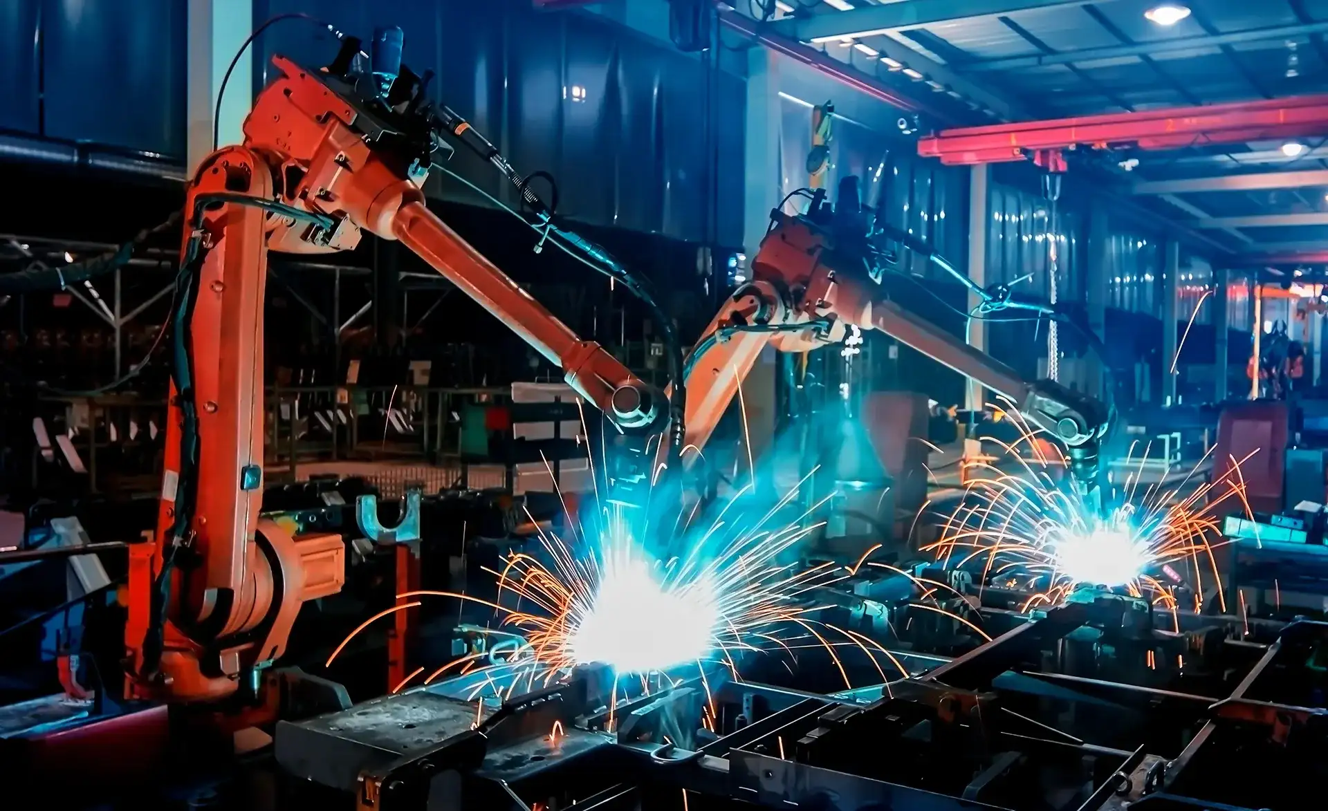 Zwei große Schweißroboter erzeugen Funken während automatisierter Schweißarbeiten in einer Produktionshalle.