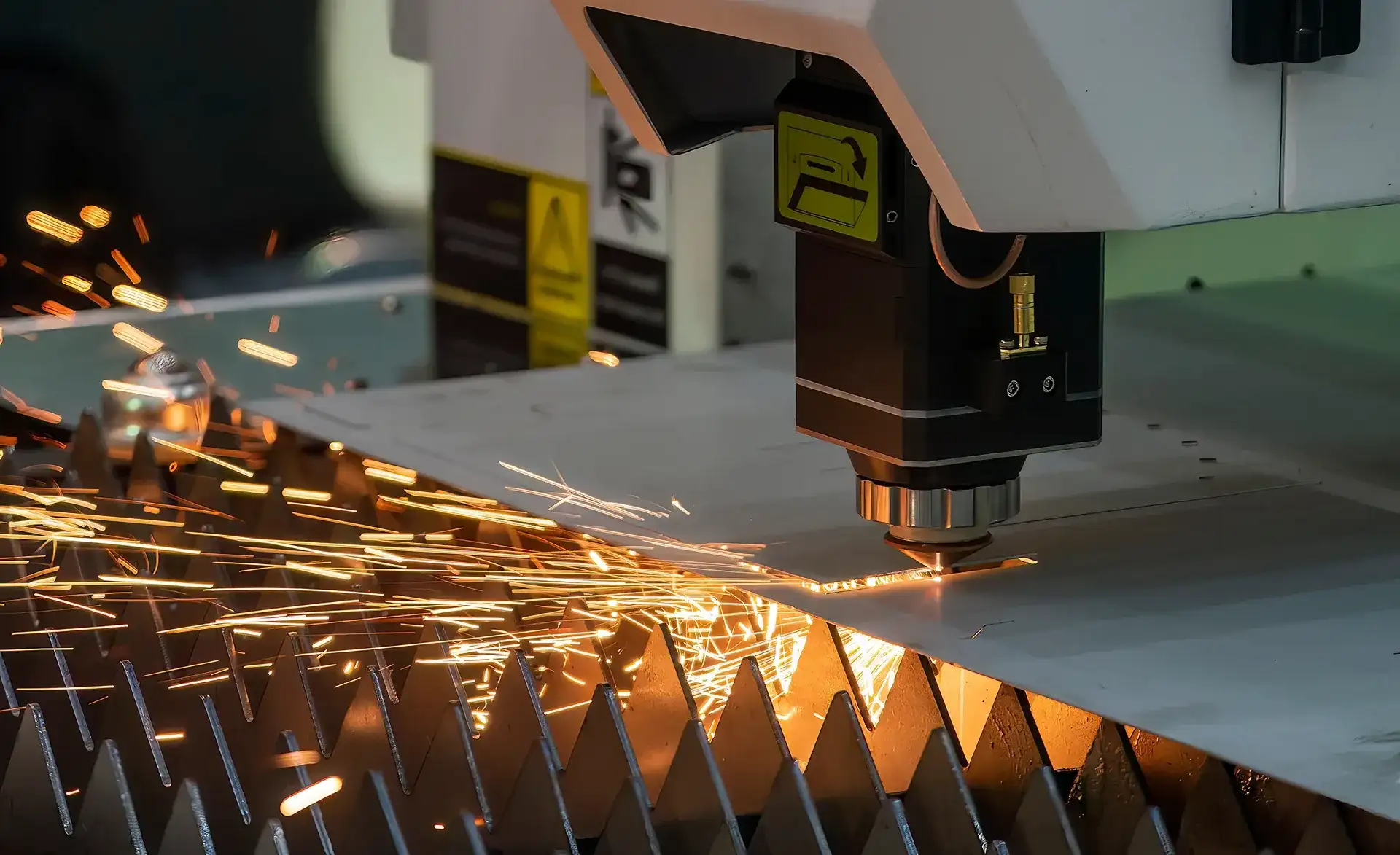 Industrieller Laserschneider, der Funken sprühend eine Metallplatte bearbeitet.