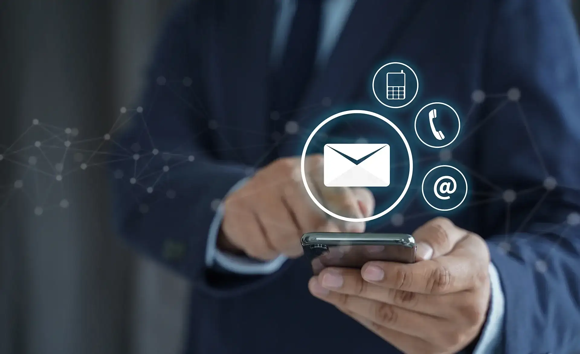 Person im Anzug bedient ein Smartphone, darüber eingeblendet Symbole für E-Mail, Telefon und Kontakt.